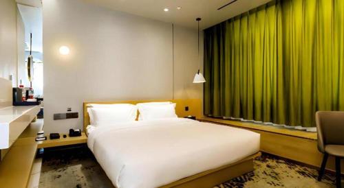 a bedroom with a large bed and a green curtain at Borrman Hotel Jining High-tech Huangtun in Jining