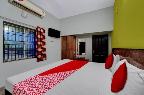 a bedroom with a red and white bed with a window at Hotel O Elite Residency in Chennai