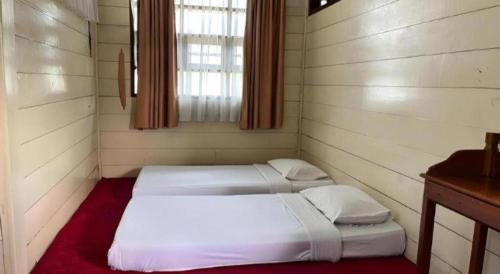 two beds in a room with a window at Sapadia Hotel Parapat in Parapat