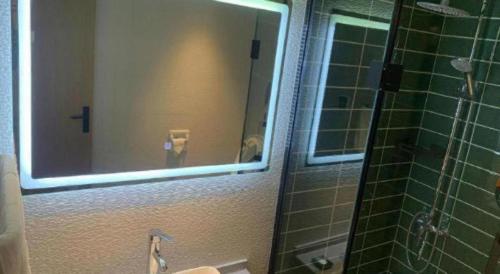 a bathroom with a mirror and a sink and a shower at GreenTree Inn Luoyang Henan University of Science and Technology in Luoyang
