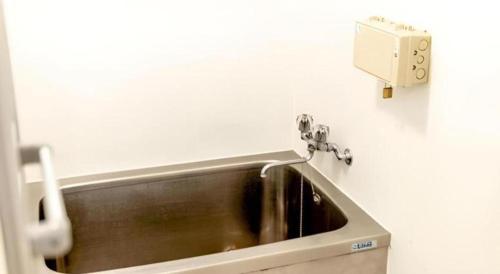 a stainless steel sink in a bathroom with a soap dispenser at HOSTEL LUND I -Oimachi- in Tokyo