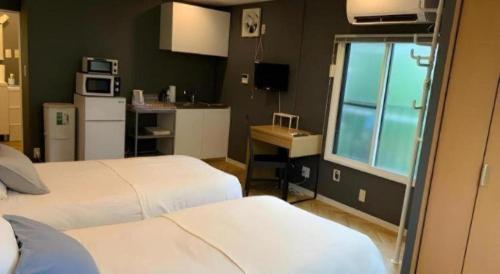 a bedroom with two beds and a kitchen with a window at HOSTEL LUND I -Oimachi- in Tokyo