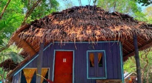 a hut with a thatch roof and a red door at Longbeach Kohphayam in Ko Phayam