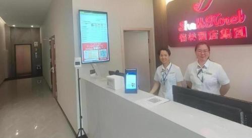 two women standing at a counter in a store at Shell Hotel Wuxi Huishan District Chang'an Town in Wuxi