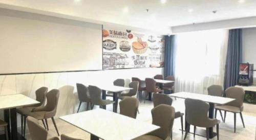 a dining room with tables and chairs and a white wall at GreenTree Inn Express Fuyang University Town West High-Speed Railway Station in Fuyang