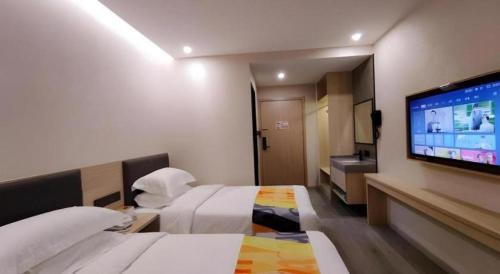 a hotel room with a bed and a flat screen tv at Shell Hotel Wuxi Huishan District Chang'an Town in Wuxi