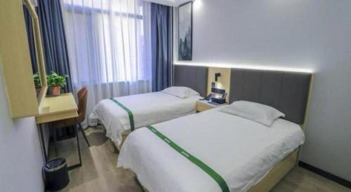 a hotel room with two beds and a desk at GreenTree Inn Express Fuyang University Town West High-Speed Railway Station in Fuyang