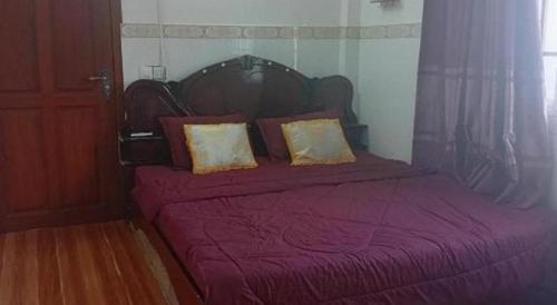 a bed with a purple blanket and two pillows at Unique Hotel in Phnom Penh