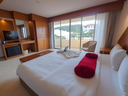 a bedroom with a large white bed with a red pillow at Hack Patong Beach Hotel in Patong Beach