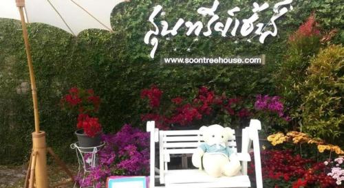 a teddy bear sitting on a white bench in a garden at Soontree House Hotel in Udon Thani