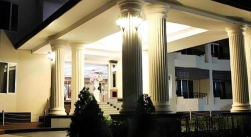 a building with white columns with christmas trees in front at Siamtara Palace Hotel in Maha Sarakham