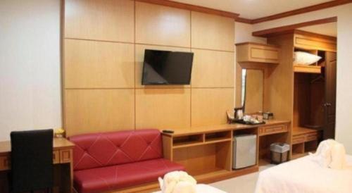 a hotel room with a red chair and a television at Siamtara Palace Hotel in Maha Sarakham