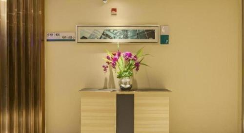 a vase of flowers on a table in a room at City Comfort Inn Wuhan Jiefang Avenue Xinrong Light Rail Station in Wuhan