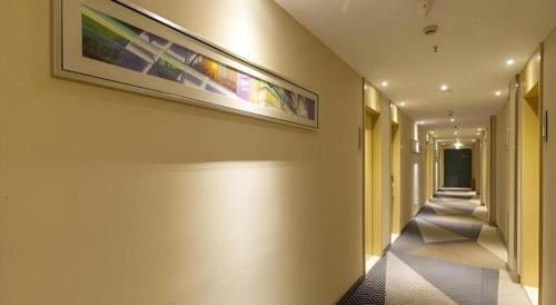 a hallway with a painting on the wall and a long corridor at City Comfort Inn Wuhan Jiefang Avenue Xinrong Light Rail Station in Wuhan
