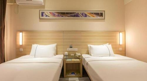 a hotel room with two beds and a table at City Comfort Inn Wuhan Jiefang Avenue Xinrong Light Rail Station in Wuhan