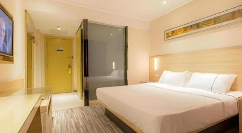 a bedroom with a large white bed and a bathroom at City Comfort Inn Wuhan Jiefang Avenue Xinrong Light Rail Station in Wuhan