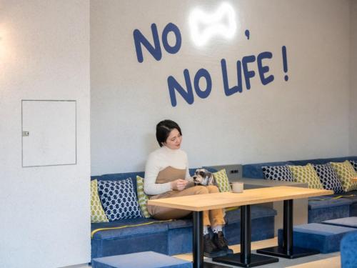 a woman sitting at a table with a dog at hotel anddoggy Kyoto Nijo in Kyoto
