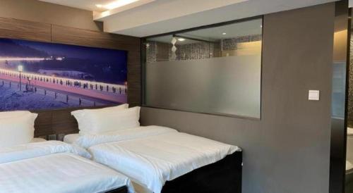 two beds in a room with a picture on the wall at J Link Hotel in Hong Kong