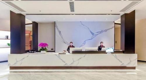 two people sitting at a reception desk in a lobby at Borrman Hotel Chongqing Bishan Central Street in Chongqing