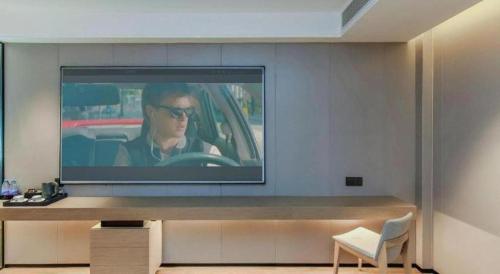 a television on a wall with a woman driving a car at Borrman Hotel Chongqing Bishan Central Street in Chongqing