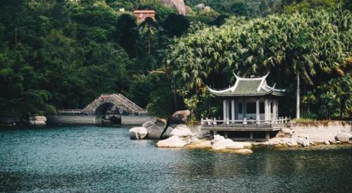 a bridge over a lake with a building in the water at Xiamen Seashine Lakeview Hotel in Xiamen