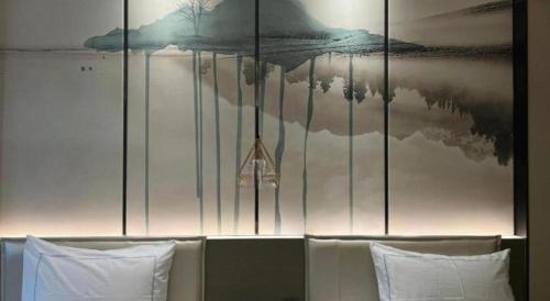 a wall with a painting above a bed with white pillows at Xiamen Seashine Lakeview Hotel in Xiamen