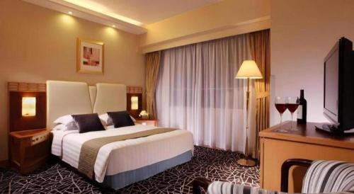 a hotel room with a large bed and a television at OASIS AVENUE-A GDH HOTEL in Hong Kong