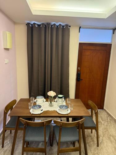 a dining room table with chairs and a black curtain at Homestay Kuala Perlis in Kuala Perlis
