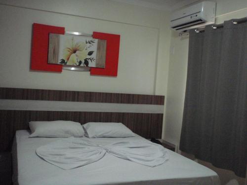 1 cama en un dormitorio con una pintura roja en la pared en Lacqua Park Caldas Novas, en Caldas Novas