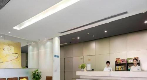 two people standing at a counter in a lobby at Jinjiang Inn Shenzhen Airport in Shenzhen