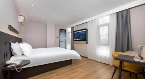 a hotel room with a bed and a desk with a phone at Jinjiang Inn Shenzhen Airport in Shenzhen