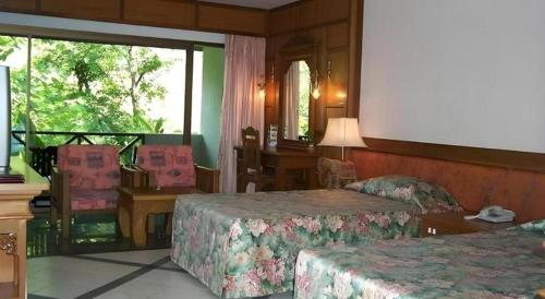 a hotel room with two beds and a table and chairs at River Kwai Village Hotel in Ban Kaeng Raboet