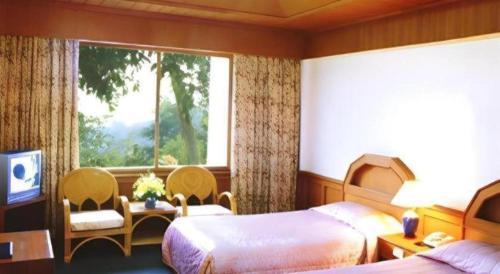 a hotel room with two beds and a window at Pailyn Hotel in Sukhothai