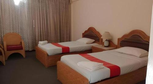 a hotel room with two beds and a chair at Pailyn Hotel in Sukhothai