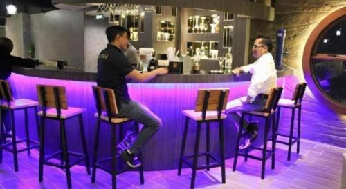 two men sitting on bar stools at a bar at Hermes Palace Hotel Medan in Medan