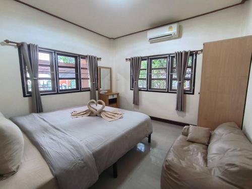 a bedroom with a bed and a couch and windows at Bp HOUSE in Nakhon Phanom