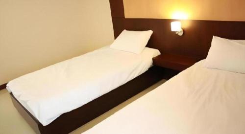 two beds in a hotel room with white sheets at 777Bliss Hometel in Nakhon Phanom