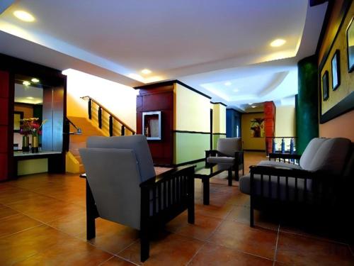 a living room with couches and chairs and a staircase at MO2 Westown Hotel San Juan in Bacolod