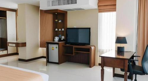 a hotel room with a bed and a television and a desk at Aramis Hotel in Nakhon Sawan