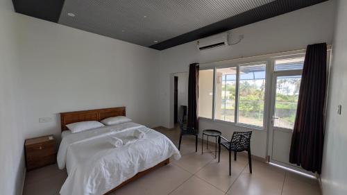a bedroom with a bed and a table and chairs at Grand Beach Villa in Kannur