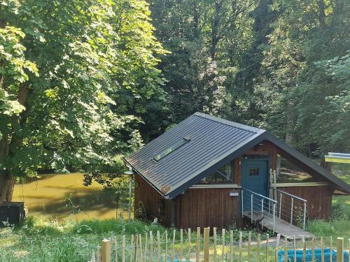 a small building with a blue door in a field at Bootshaus Froschkönig übernachten über dem Weiher in Hundsdorf