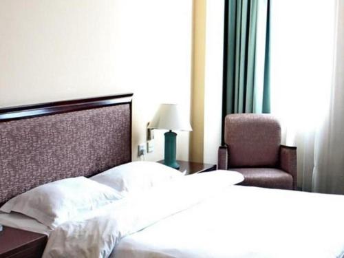 a bedroom with a bed and a chair and a lamp at Traders Inn Brunei in Bandar Seri Begawan