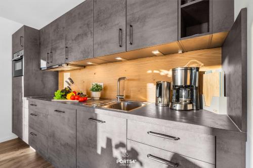 eine Küche mit grauen Schränken und einer Spüle in der Unterkunft Meerverliebt in Büsum