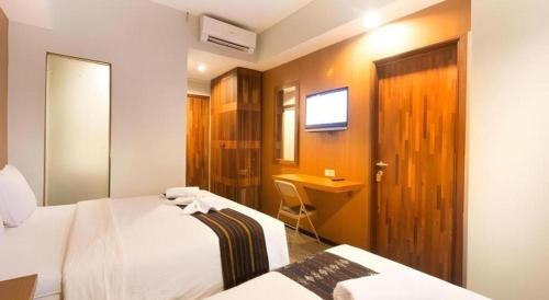 a hotel room with two beds and a desk at Hadi Poetra Hotel in Kuta