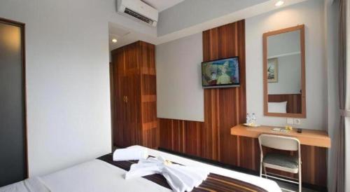 a bedroom with a bed and a desk and a mirror at Hadi Poetra Hotel in Kuta