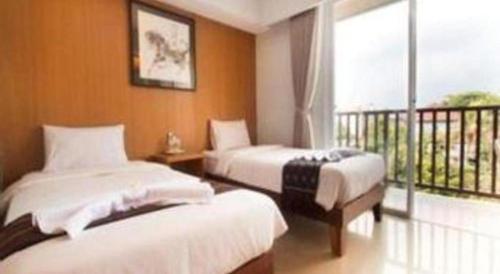 two beds in a room with a balcony at Hadi Poetra Hotel in Kuta