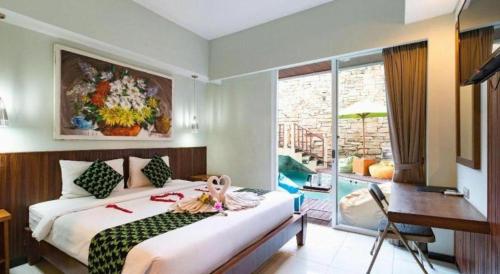 a bedroom with a bed and a desk and a window at Hadi Poetra Hotel in Kuta