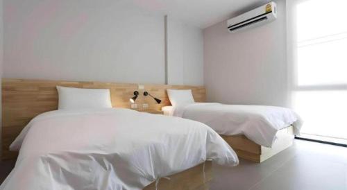 a white bedroom with two beds and a window at Esy Hotel in Lamphun