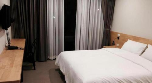 a bedroom with a white bed and a desk and a bed sidx sidx at Esy Hotel in Lamphun