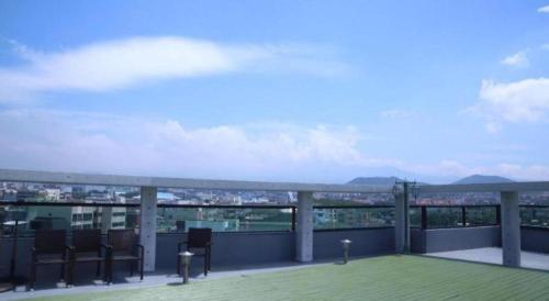 a balcony with chairs and a view of a city at Galaxy Hotel in Jeju